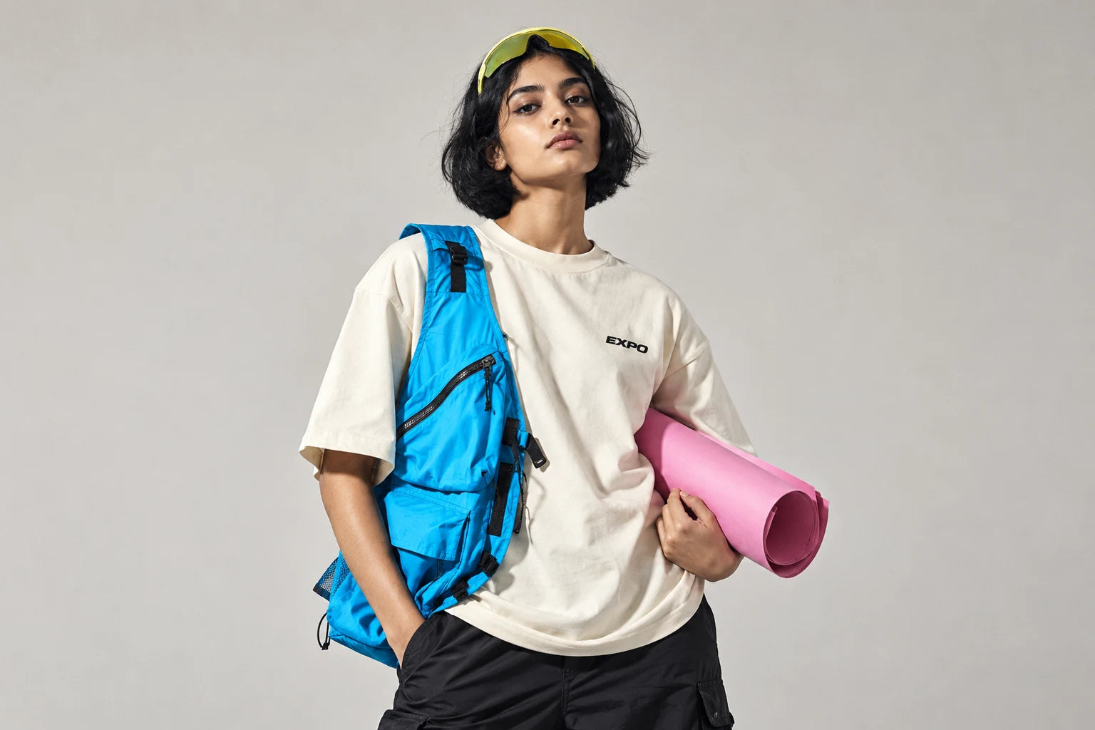 Model in the Colour Theory Tee with a cyan sling bag and a pink mat