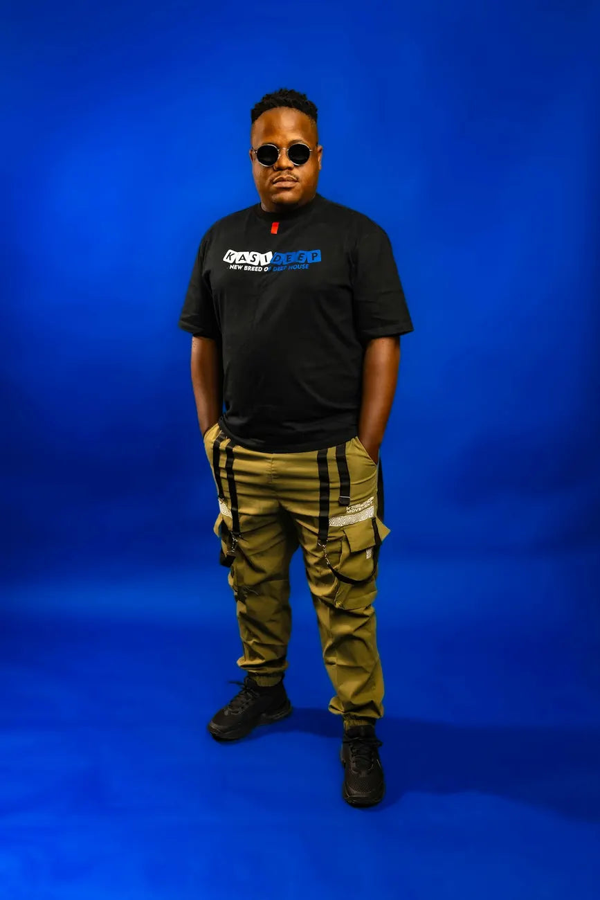 Man in sunglasses and cargo trousers against a cobalt wall