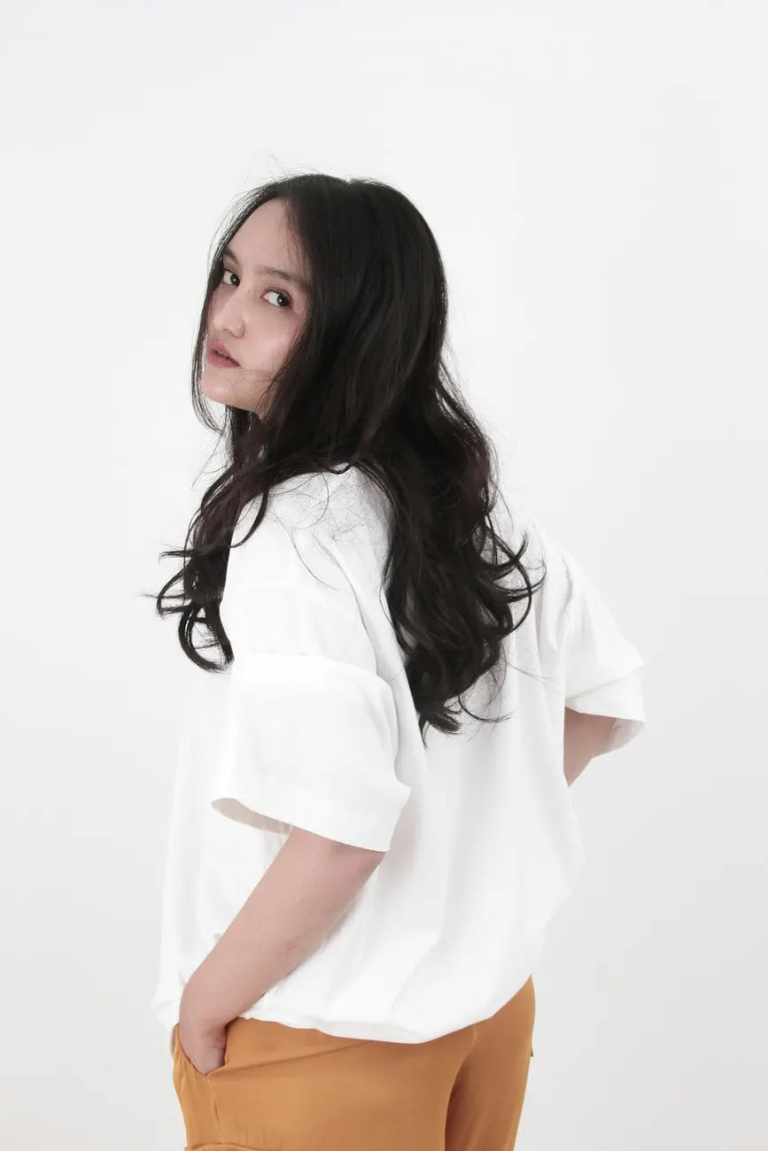 Woman in an oversized white tee looking back over her shoulder