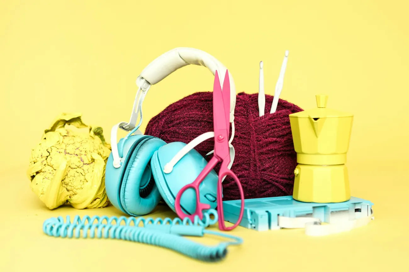 Bright objects on a yellow surface: headphones, yarn, scissors