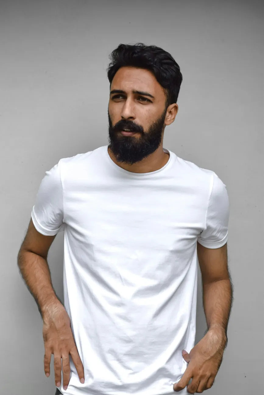 Portrait of a man in a plain white tee against a grey studio wall