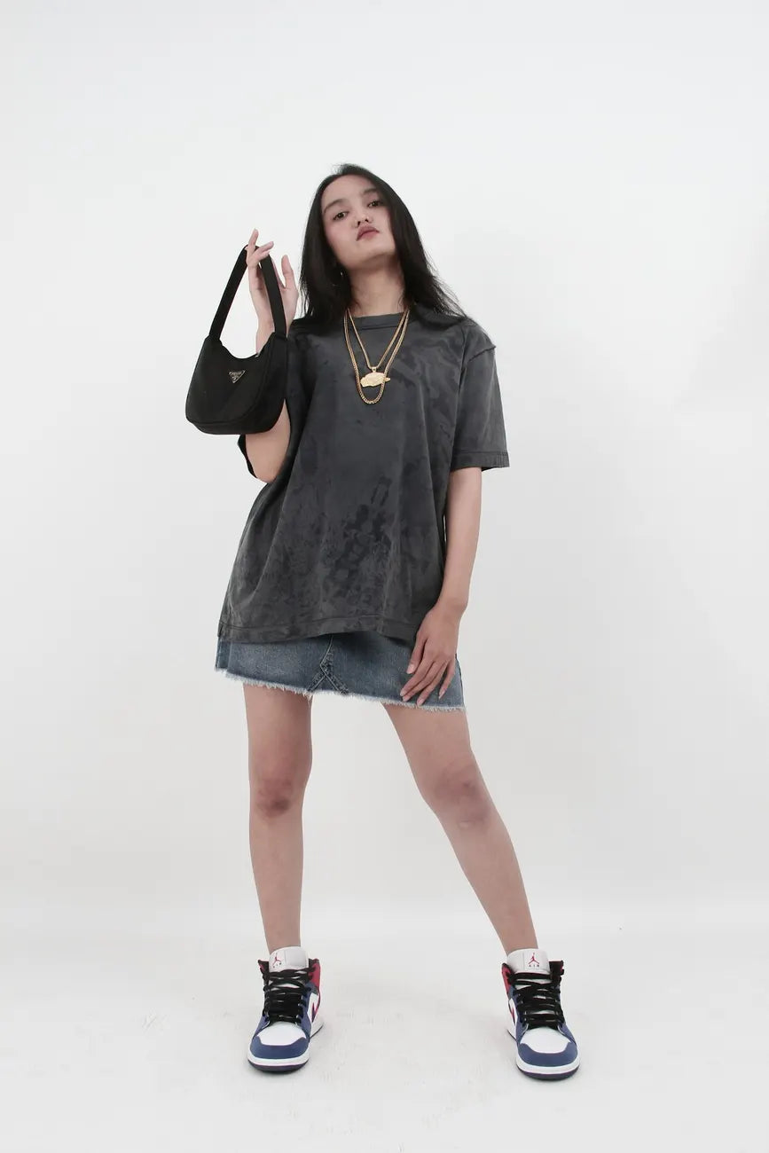 Woman in an oversized tee and sneakers in a grey studio